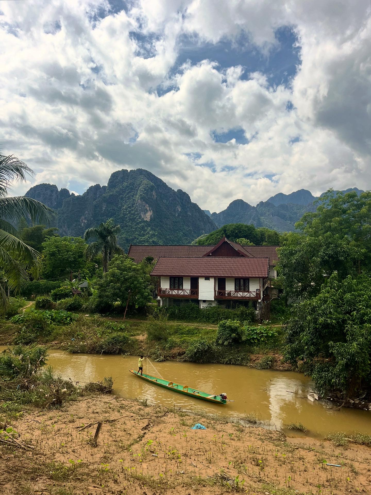 A building next to a brown river with mountains in the background